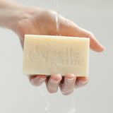 Hand holding a bar of Soap Superieure, Gaelle Organic's moisturing cleanser, on a white background