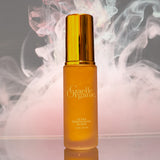 Ultra Contouring Elixir, the best serum for sagging skin, on a reflective base with wisps of pink in the background.