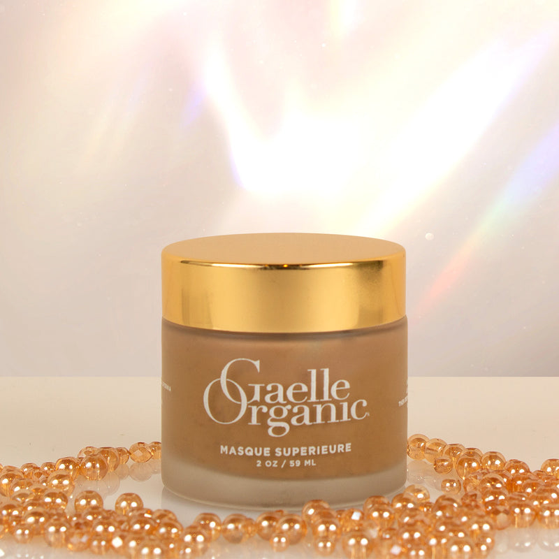Masque Superieure, an organic hydrating masque for all skin types, with golden shining beads on a white surface.