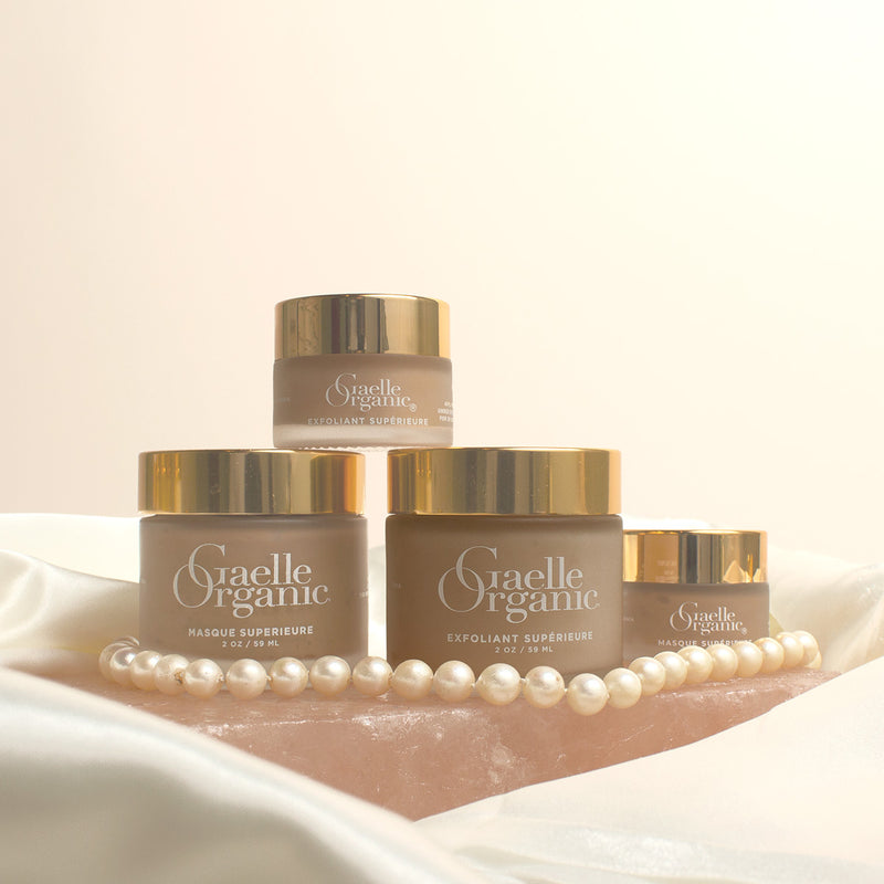 The Gaelle Organic Signature Treatment for mature skin, consisting of full and travel size Exfoliant Superieure and Masque Superieure, on a quartz slab with pearls and plain background