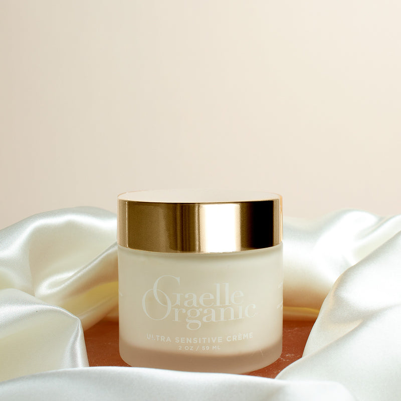Ultra Sensitive Creme, a natural moisturizer for sensitive dry skin, on a pink stone with a silk scarf